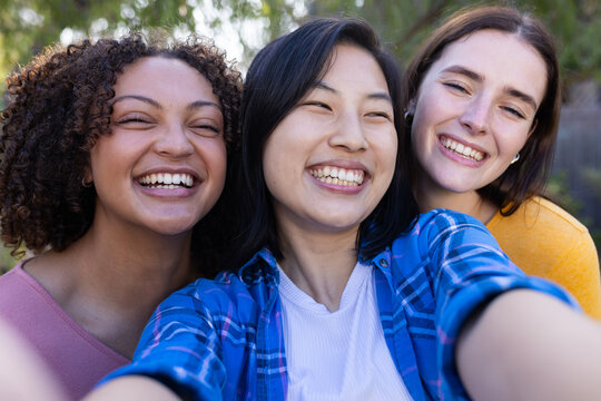 Smiling friends taking selfie together outdoors, enjoying time and bonding