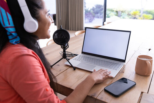 Recording podcast, woman using laptop and microphone with headphones at home, copy space