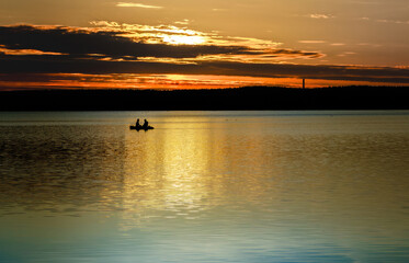 Fishermen in a boat on the lake at dawn at sunrise.