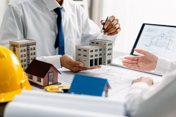 Team architects discuss modern building model and working with plans on a blueprint in the office, development low residence projects, design home custom of customer, build a housing estate.