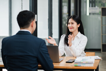 Two colleagues having a productive business meeting in a modern office, discussing work with a laptop and documents on the table.