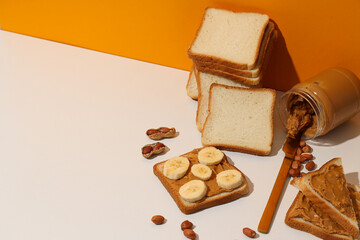 Peanut paste in a glass jar with toast, on a light background.
