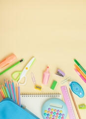School supplies on a light yellow background. stationery, including pencils, markers, and scissors in a blue case, along with a calculator and notebooks. Back to school concept