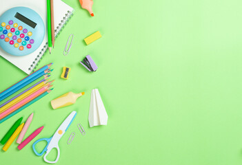 School stationery and paper airplane on green background. Back to school concept. School supplies. Plan, top view.