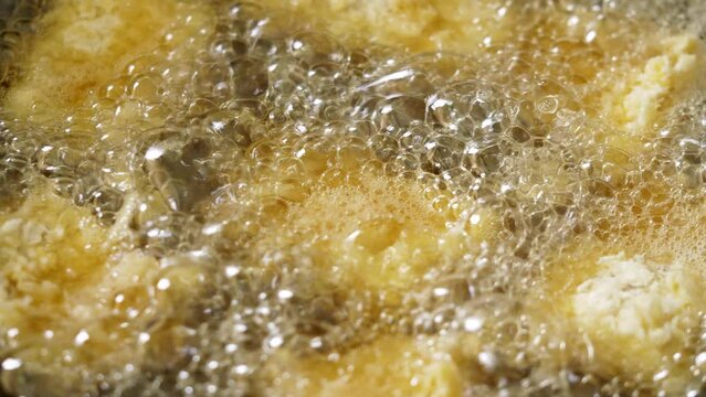 Cook is frying fish in a hot pan in a restaurant kitchen.