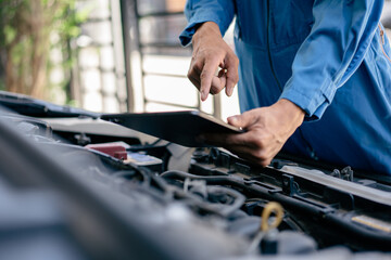 Automotive mechanic repairman using tablet to checking engine room, check the mileage of the car, oil change, car auto service, auto maintenance service concept.