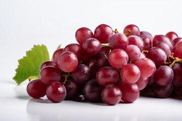 Fototapeta premium A bunch of fresh ripe juicy organic red grapes with green leaves isolated on white background