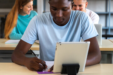 Close up of teen African American male student using digital tablet in class. Black high school student doing homework.
