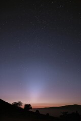 The ethereal beauty of the zodiacal light, a faint glow visible in the pre-dawn sky, heralding the arrival of a new day, Generative AI (
