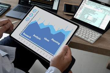 A businessman with a tablet graph in his hand examining In the office, a statistical financial chart report document Technology for business reports