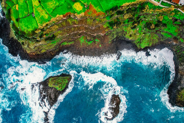 Aerial view of rough ocean with waves, volcanic beach and swiming pool in Seixal, Madeira, Portugal