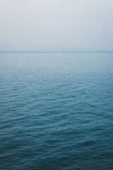 Obraz premium A bridge in the distance on a misty horizon of a lake.