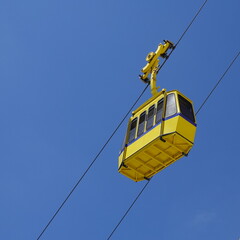 Yellow funicular car against the background of the sky and white rock. Cable road at Rosh Hanikra tourist site. Tourism Concept