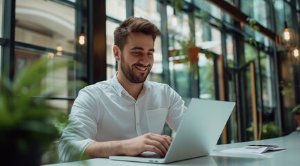 Fototapeta premium happy male accountant with income tax documents and laptop working at desk in a modern office with a glass-wall interior.