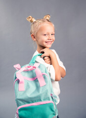 A happy girl holds a school backpack on her shoulders, back to school, school days, the child goes to classes, close-up, portrait of a girl.