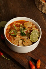Indonesian spicy soup food on a white bowl with a freeze and levitation photo concept, dark brown wooden background