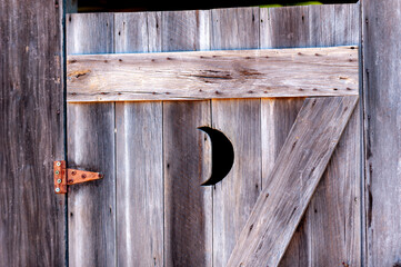 Weathered wooden door with a half-moon cut out.