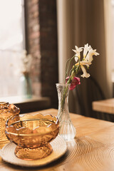 Budvase with flowers and glassware on table