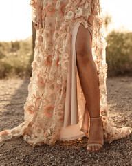 Woman's leg in pink dress in warm sunlight in desert