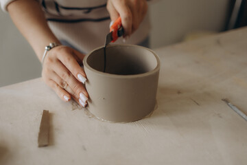 Close-up Image portrait of female ceramic artist working with clay mug and making Ceramic Product. Professional Ceramic Artist makes handcrafted products. Small business and hobby concept