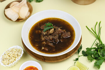 Rawon Daging Sapi or Indonesian beef black soup, traditional beef soup from East  Java, served with rice, bean sprouts, sambal, lime, and shrimp crackers.  