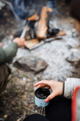 Fototapeta premium Spend time in the tranquility of the outdoors, surrounded by friends by a campfire, savoring hot beverages outside, and creating lasting memories in the wilderness