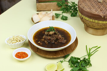 Rawon Daging Sapi or Indonesian beef black soup, traditional beef soup from East  Java, served with rice, bean sprouts, sambal, lime, and shrimp crackers.  