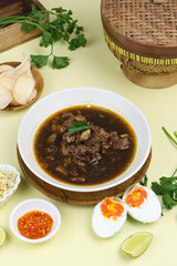 Rawon Daging Sapi or Indonesian beef black soup, traditional beef soup from East  Java, served with rice, bean sprouts, sambal, lime, and shrimp crackers.  