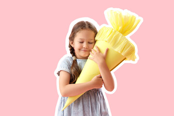 Happy little girl with yellow school cone on pink background