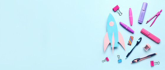 Paper rocket with different stationery on blue background