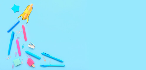 Creative composition with paper rocket and different stationery on blue background