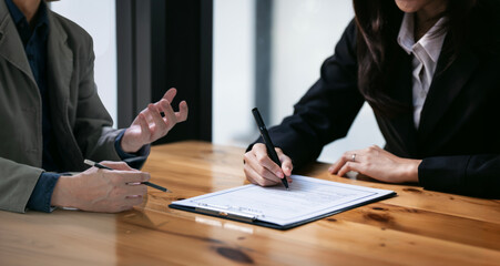 businessman and woman discussing and signing a contract in office.