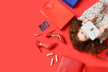 Beautiful young woman with stylish bags, high heels and lipsticks on red background