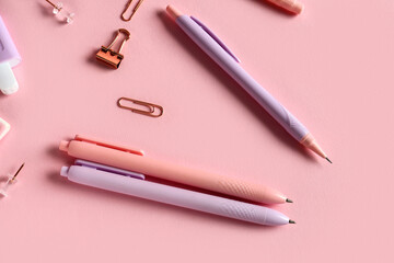 Pens with paper clips on pink background
