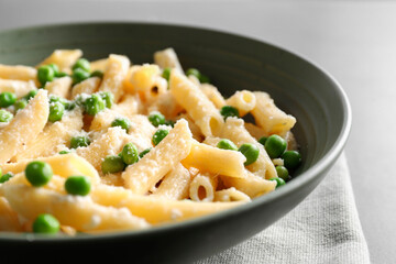 Delicious pasta with green peas and cheese on table, closeup