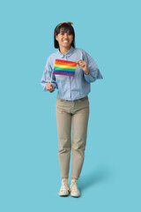 Happy young woman with LGBT flag on blue background