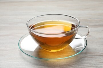 Refreshing green tea in cup on light wooden table, closeup