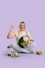 Pretty young woman with scales and fresh vegetables showing OK on lilac background. Weight loss...