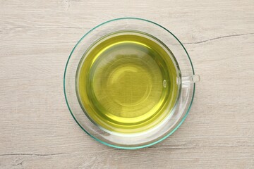 Refreshing green tea in cup on wooden table, top view