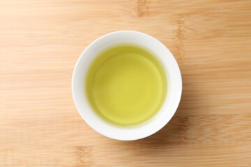 Refreshing green tea in cup on wooden table, top view