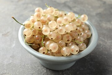 Fresh white currant berries in bowl on gray textured table, closeup