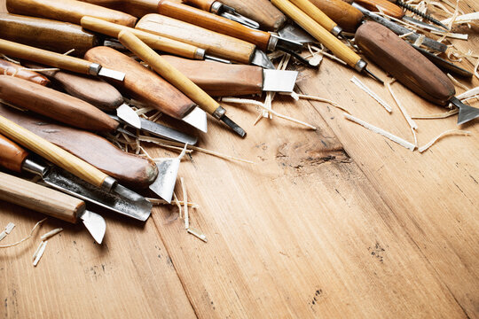 Carpentry tools on rustic wooden table top view. Handmade woodworking carving instruments with shavings for hobby and handcraft.