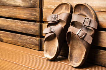 brown worn out leather sandals lean on wooden box outside