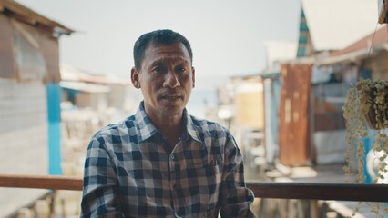 Portrait of the Indonesian man sitting outdoor with buildings on the background