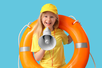 Happy little girl lifeguard with ring buoy and megaphone on blue background