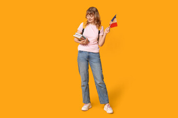 Female student with French flag and books on yellow background