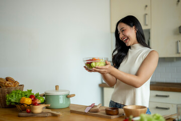 A woman is smiling and holding a bowl of salad