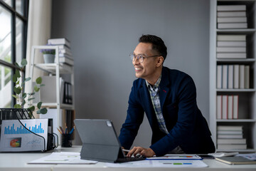 A man is sitting at a desk with a laptop and smiling