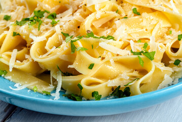 Piatto di deliziose fettuccine Alfredo, ricetta tipica di pasta all'uovo condita con burro e parmigiano, cibo italiano 