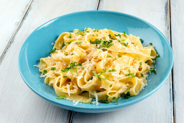 Piatto di deliziose fettuccine Alfredo, ricetta tipica di pasta all'uovo condita con burro e parmigiano, cibo italiano 